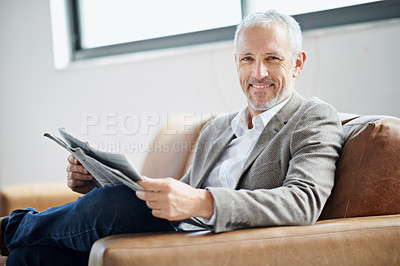 Buy stock photo Portrait of a handsome mature man relaxing with the newspaper at home