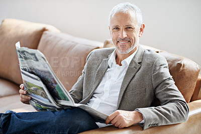 Buy stock photo Portrait of a handsome mature man relaxing with the newspaper on the sofa