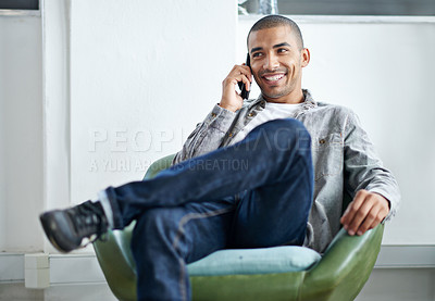 Buy stock photo Shot of a handsome young office worker talking on a cellphone while sitting in an office