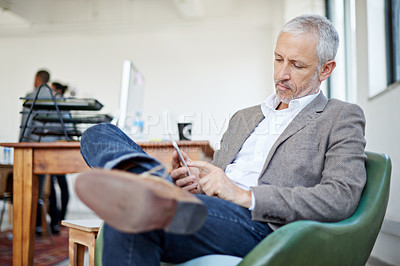 Buy stock photo Shot of a mature businessman using a cellphone while sitting in an office