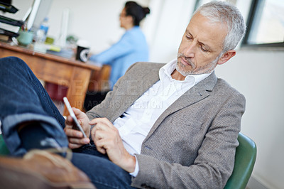 Buy stock photo Shot of a mature businessman using a cellphone while sitting in an office