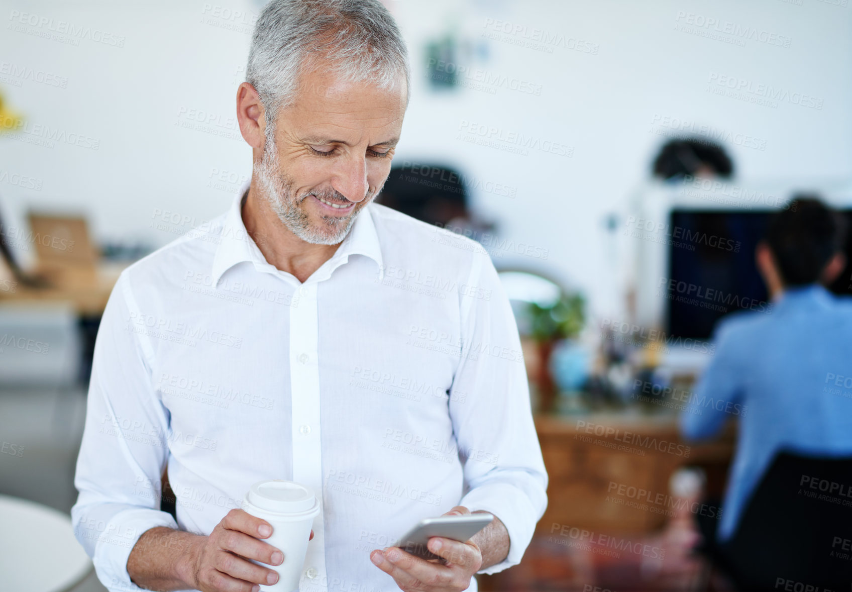 Buy stock photo Portrait of a mature businessman using a cellphone while standing in an office