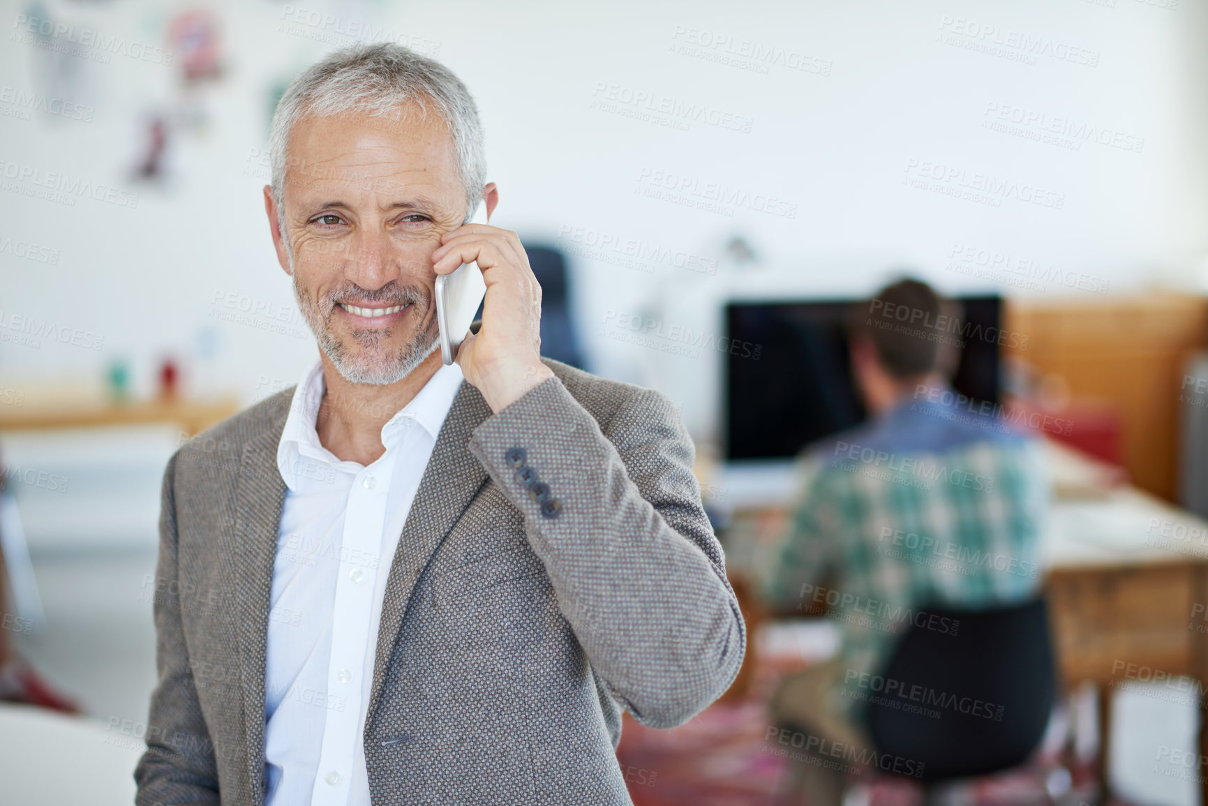 Buy stock photo Portrait of a mature businessman talking on a cellphone while standing in an office