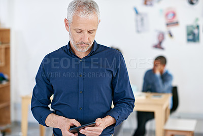Buy stock photo Shot of a handsome businessman using a digital tablet in the office. The commercial designs displayed represent a simulation of a real product and have been changed or altered enough by our team of retouching and design specialists so that they don't have copyright infringements