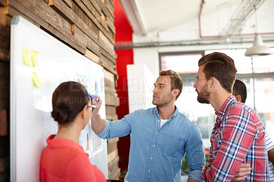 Buy stock photo Shot of a group of young designers brainstorming at a whiteboard