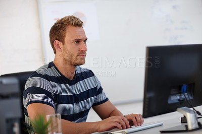 Buy stock photo Shot of a young male designer working at his computer