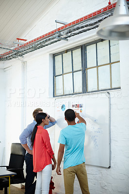 Buy stock photo Shot of a group of young designers brainstorming at a whiteboard