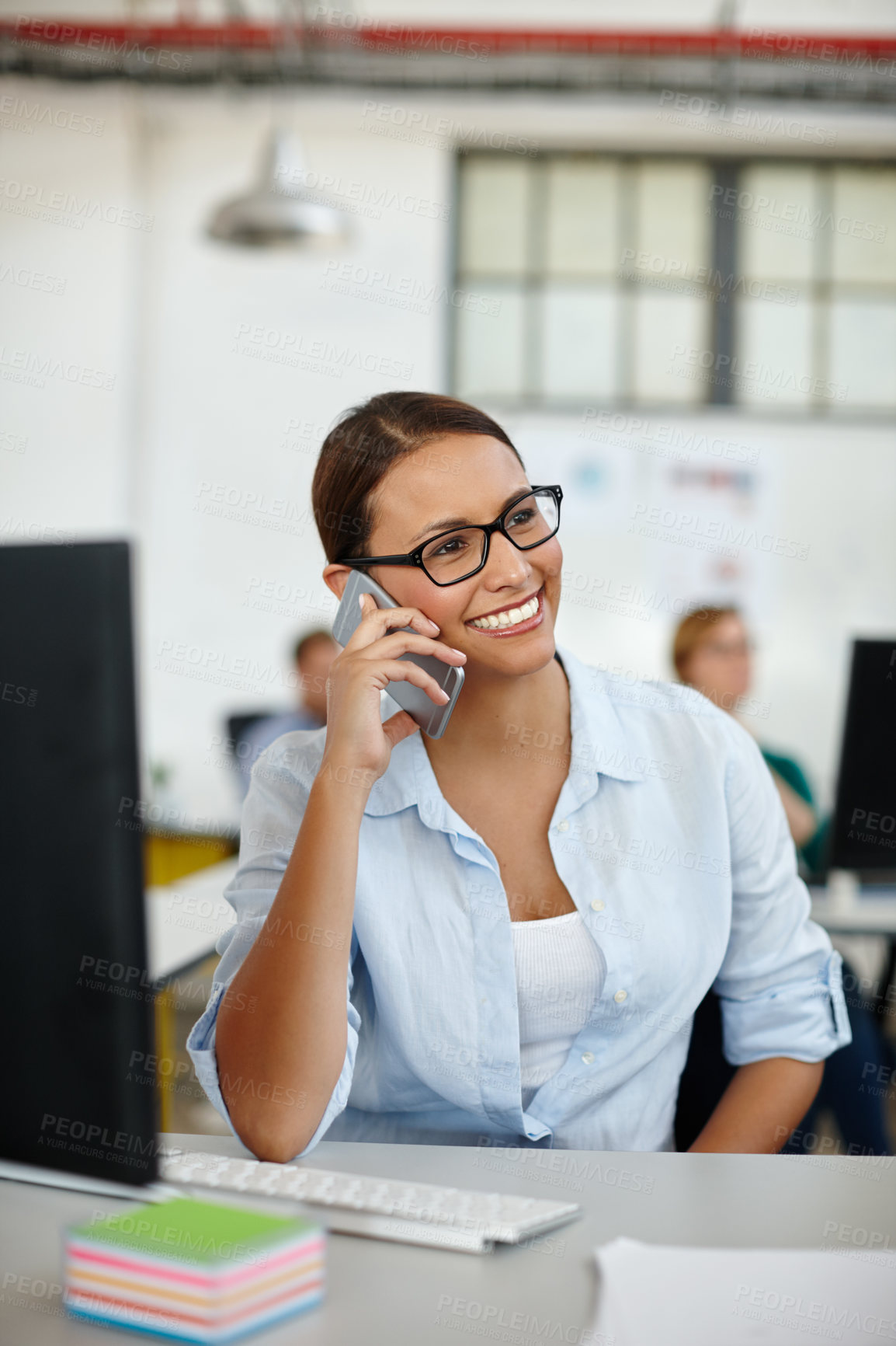 Buy stock photo Shot of a young female designer talking on the phone while sitting at her desk