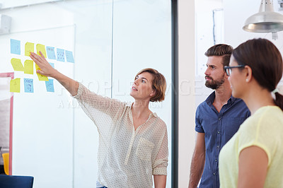 Buy stock photo Shot of a group of colleagues discussing ideas together on sticky notes