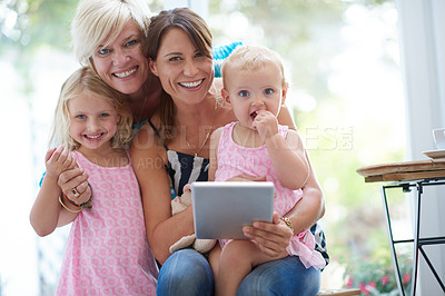 Buy stock photo Portrait of a lesbian couple showing their daughters how to use a digital tablet