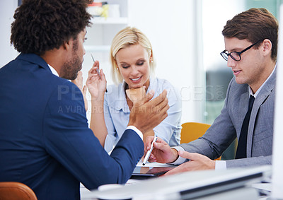 Buy stock photo Shot of three colleagues in an office looking at a digital tablet

