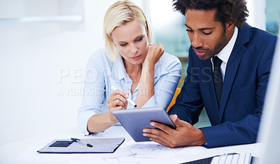 Buy stock photo Shot of two businesspeople looking seriously at a digital tablet
