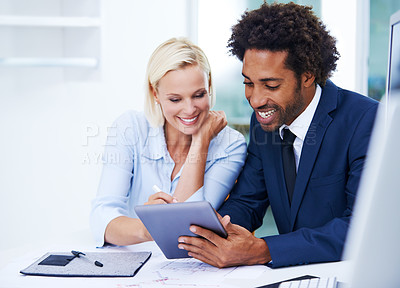 Buy stock photo Shot of a male and female colleague discussing something on a digital tablet