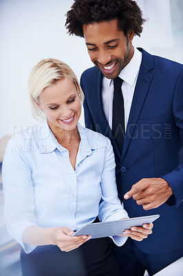 Buy stock photo Shot of a male and female colleague looking at something on a digital tablet