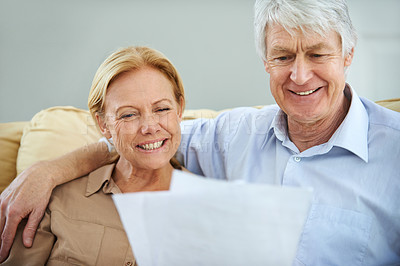 Buy stock photo Shot of a happy elderly couple going over their paperwork together at home