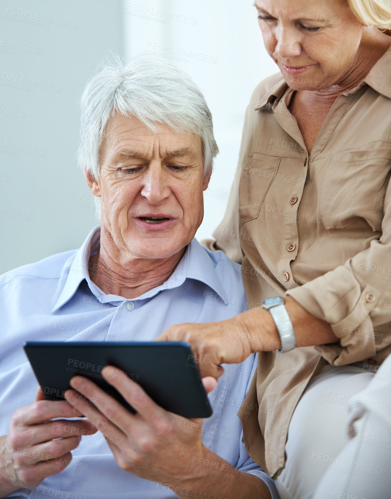 Buy stock photo Shot of a happy elderly couple using a digital tablet together at home