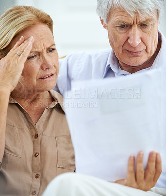 Buy stock photo Shot of an elderly couple looking frustrated while going over their paperwork together  