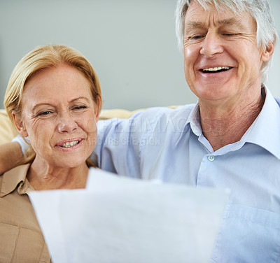 Buy stock photo Shot of a happy elderly couple going over their paperwork together at home