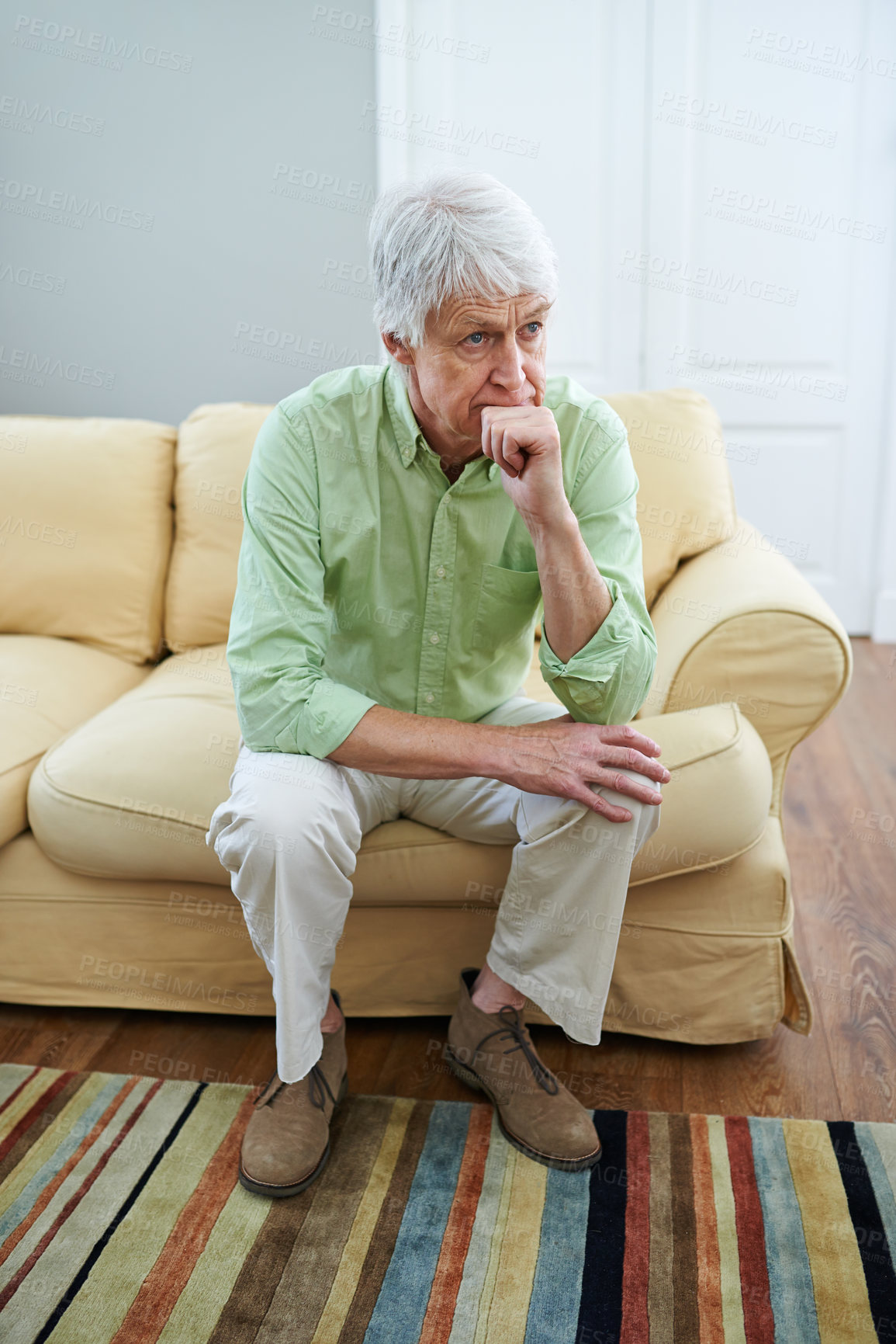 Buy stock photo Senior man thinking at home, sitting on a sofa in the living room. Worried older male concerned about pension and retirement. Sad mature man alone in his house, in mourning after death of his spouse