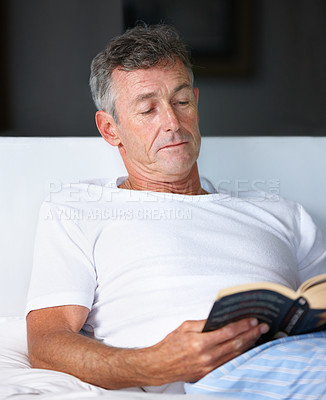 Buy stock photo A mature man sitting in bed and reading a book. A comfortable retired senior relaxing in his room starting the day inspired and motivated, gaining valuable new insights and ideas with literature