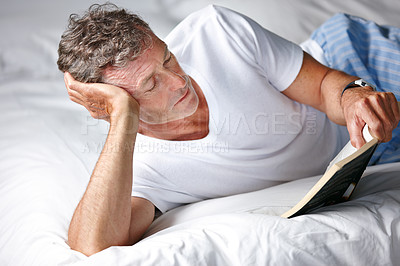 Buy stock photo Shot of a mature man reading a book in bed