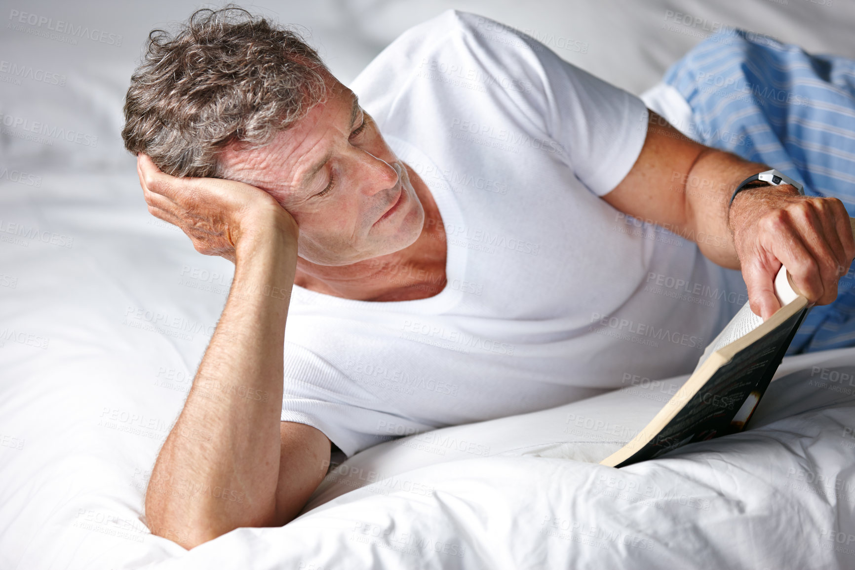 Buy stock photo Shot of a mature man reading a book in bed