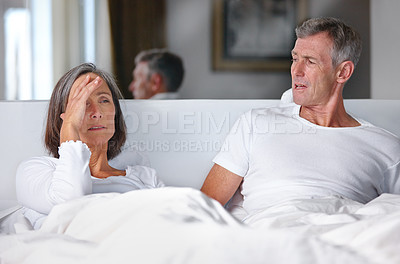 Buy stock photo Shot of a mature married couple having an argument in the bedroom