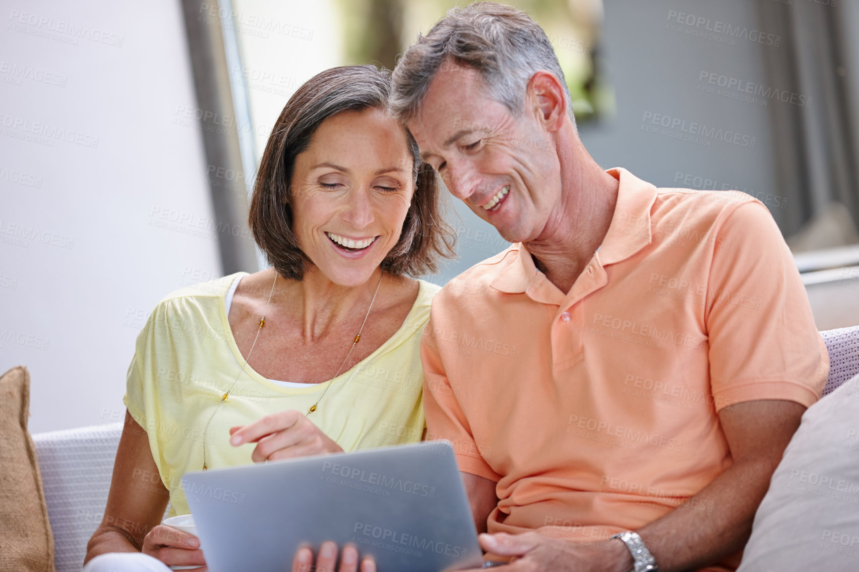 Buy stock photo Shot of a loving mature couple using a digital tablet at home