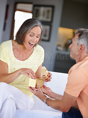Buy stock photo Shot of an attractive mature woman receiving a gift from her husband