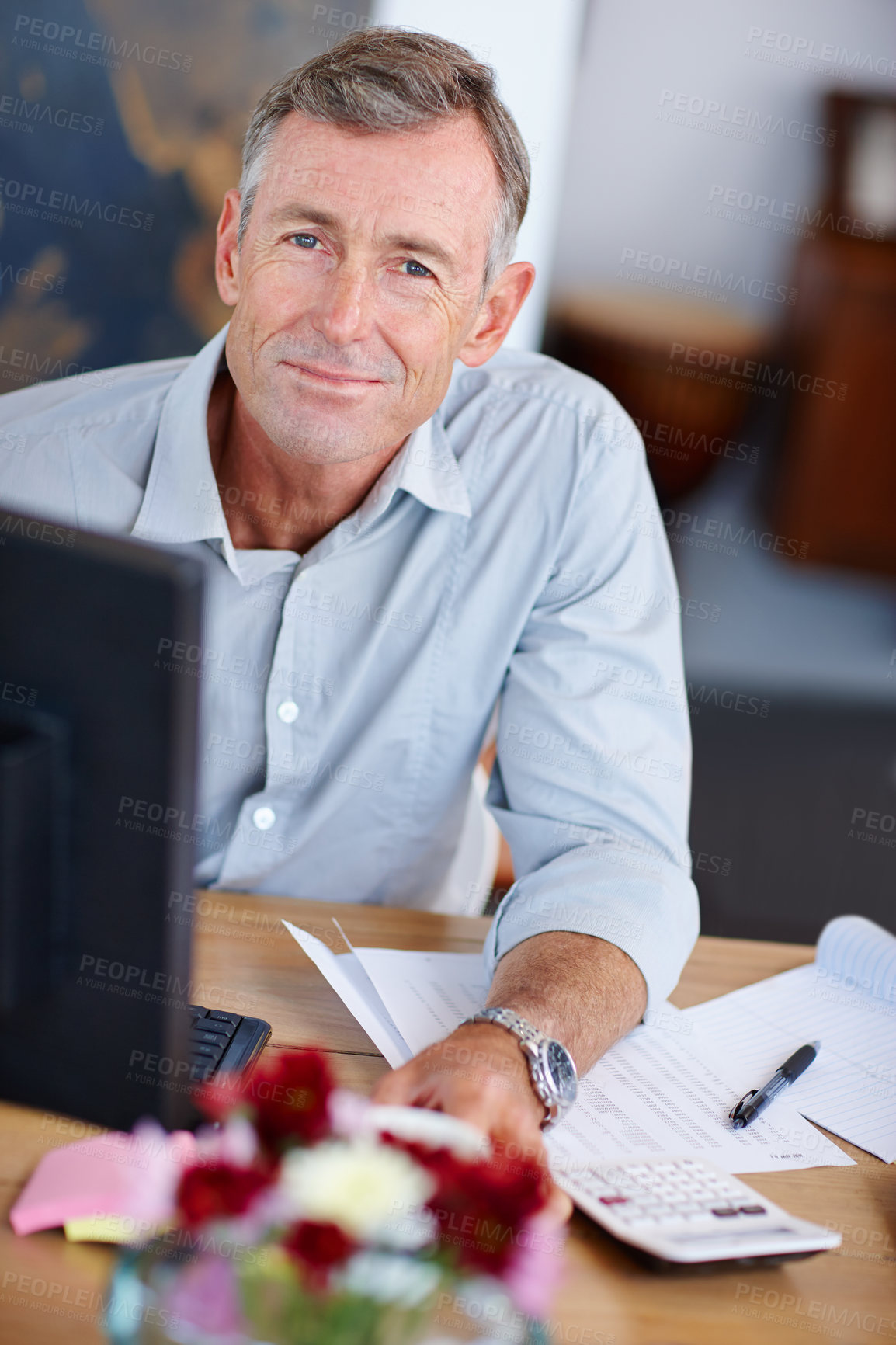 Buy stock photo Smiling freelance accountant working online while sitting with paperwork and calculator at his desk. Happy mature man sitting in front of a computer at home doing his finances and monthly budget. 