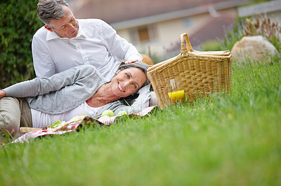 Buy stock photo Shot of a loving mature couple having a picnic on the grass