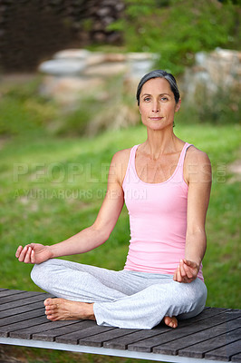 Buy stock photo Shot of an attractive mature woman practicing yoga in the lotus position