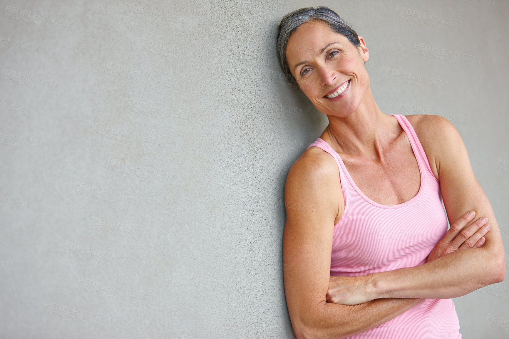 Buy stock photo Portrait of an attractive mature woman in gymwear leaning against a gray wall