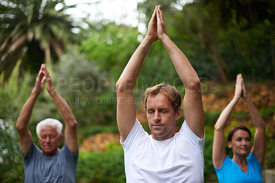 Buy stock photo Shot of a young man leading a breathing exercise in an outdoor yoga class