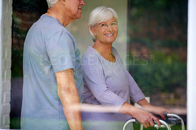 Buy stock photo Happy couple, elderly and walker to help for support, love or care in home for health by window. Man, walking frame and assist senior woman with disability for retirement, rehabilitation and recovery