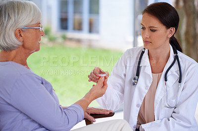 Buy stock photo Shot of a doctor handing some medication over to a senior patient
