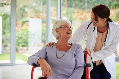 Buy stock photo Shot of a happy senior woman in a wheelchair talking with her doctor