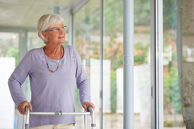 Buy stock photo Shot of a senior woman using an orthopedic walker indoors