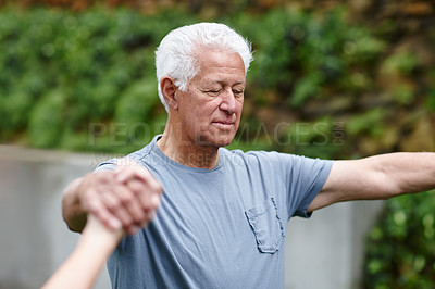 Buy stock photo A focused senior male yoga coach or instructor holding hands with a group of people during meditation. Fitness yogi standing in a circle outside at a yoga exercise class or fitness retreat weekend