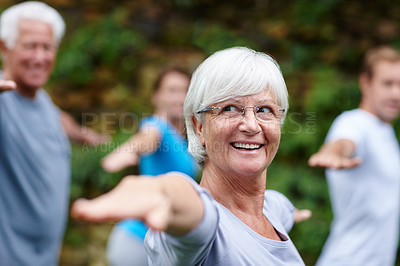 Buy stock photo Shot of a senior woman doing yoga with other people outdoors