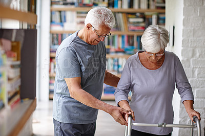 Buy stock photo Shot of a senior man assisting his wife who's using a walker for support