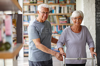 Buy stock photo Portrait of a senior man assisting his wife who's using a walker for support