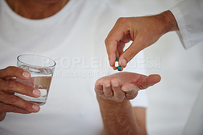Buy stock photo Closeup shot of a senior patient getting his medication from a doctor while holding a glass of water