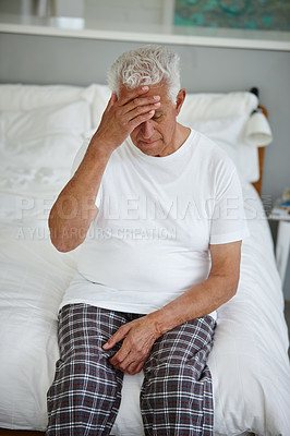 Buy stock photo Shot of a senior man looking despondent while sitting on his bed at an assisted living facility