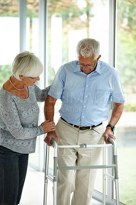Buy stock photo Shot of a senior woman helping her husband to walk with his walker