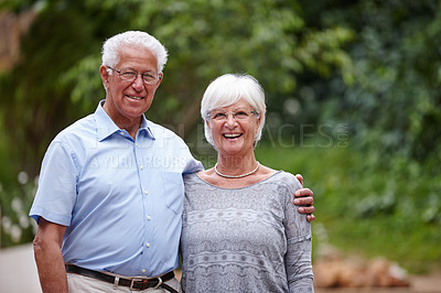 Buy stock photo Shot of a happy senior couple standing outdoors while smiling at the camera