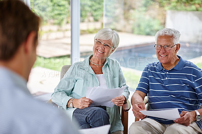 Buy stock photo Over-the-shoulder shot of a financial advisor meeting with a senior couple at their home