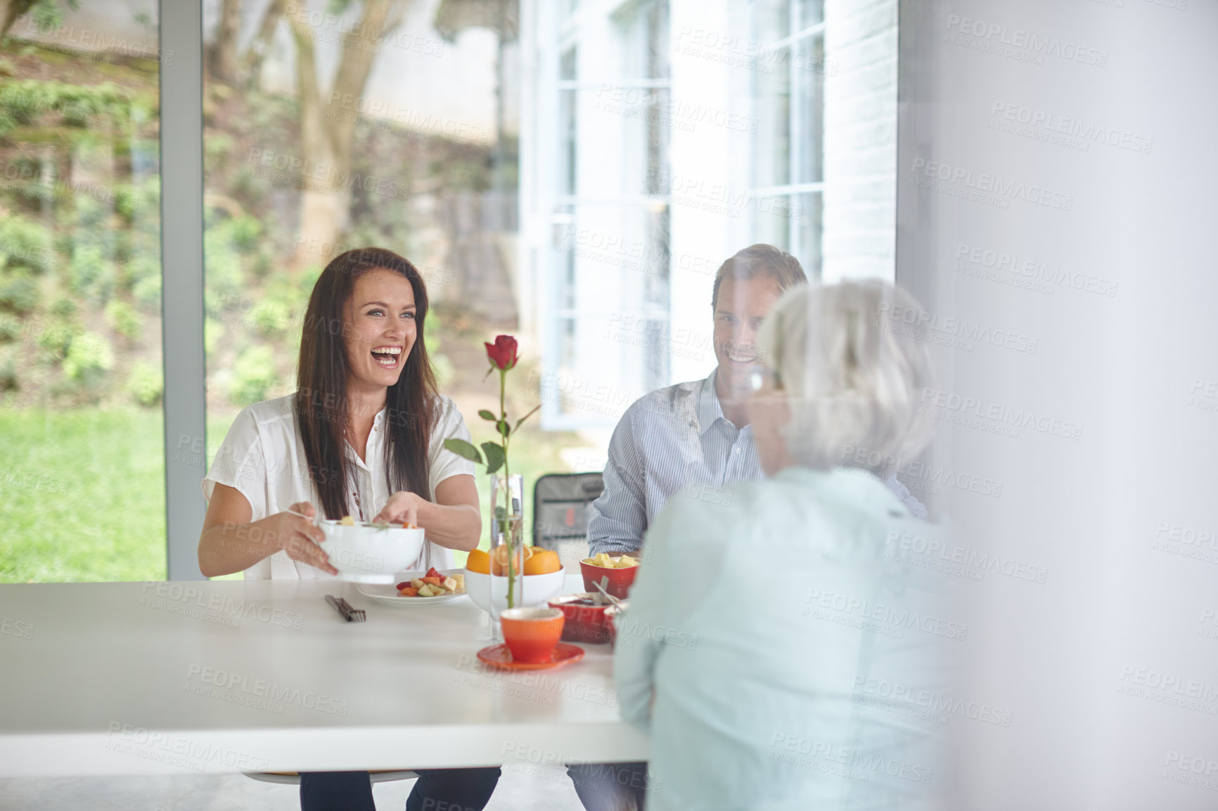 Buy stock photo Breakfast, laughing and smile with family in dining room of home together for bonding or weekend visit. Conversation, food and funny with happy people eating meal in apartment for diet or nutrition