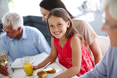 Buy stock photo Shot of a little girl having lunch with her family around the dining room table