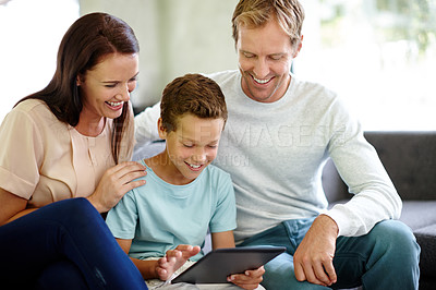 Buy stock photo Shot of a family using a digital tablet while sitting on the sofa at home